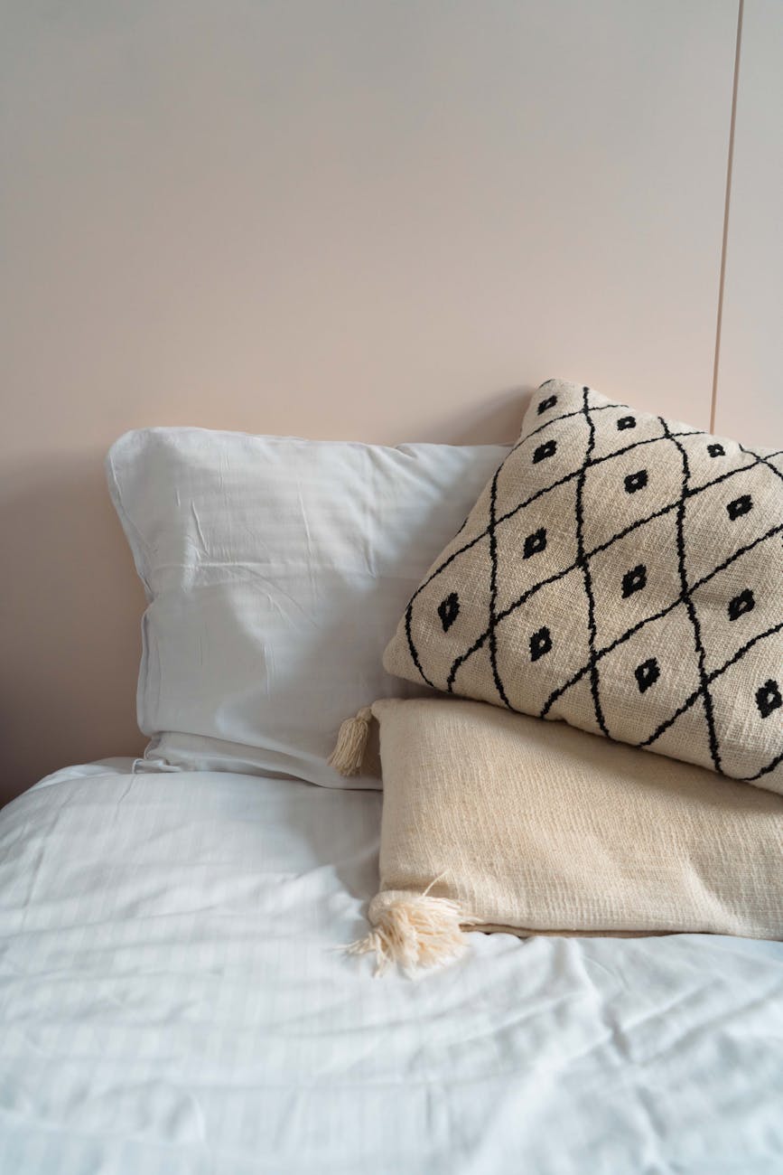 cozy white bed with patterned pillow